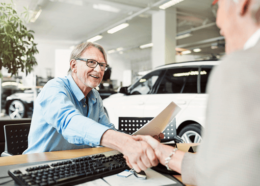 Man signing paperwork at car dealership.