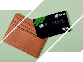 An ICCU Premier Rewards credit card beside a brown wallet on a green background.