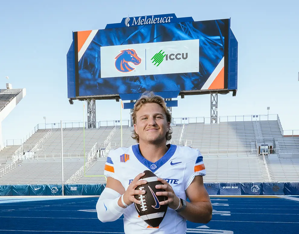 Boise State Football student-athlete Maddux Madsen posing in front of Broncos and ICCU logos.