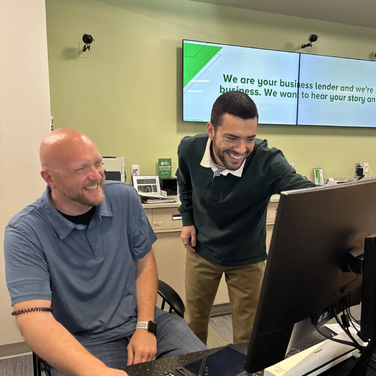 Darian Miles and a team member laughing and looking at a computer screen