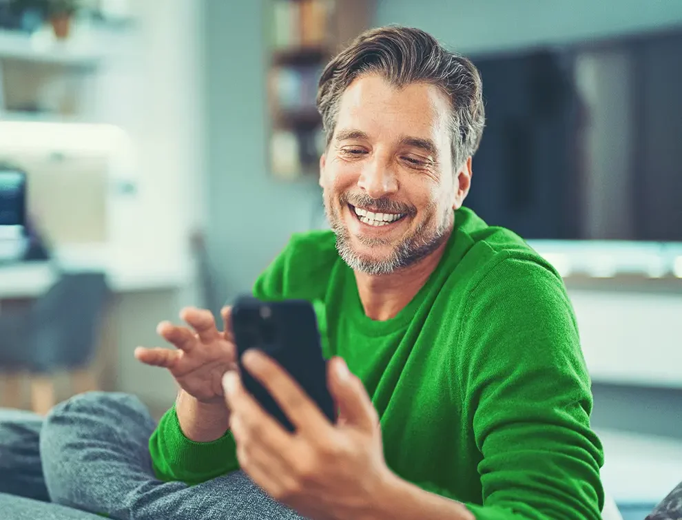 man smiling while looking at his phone