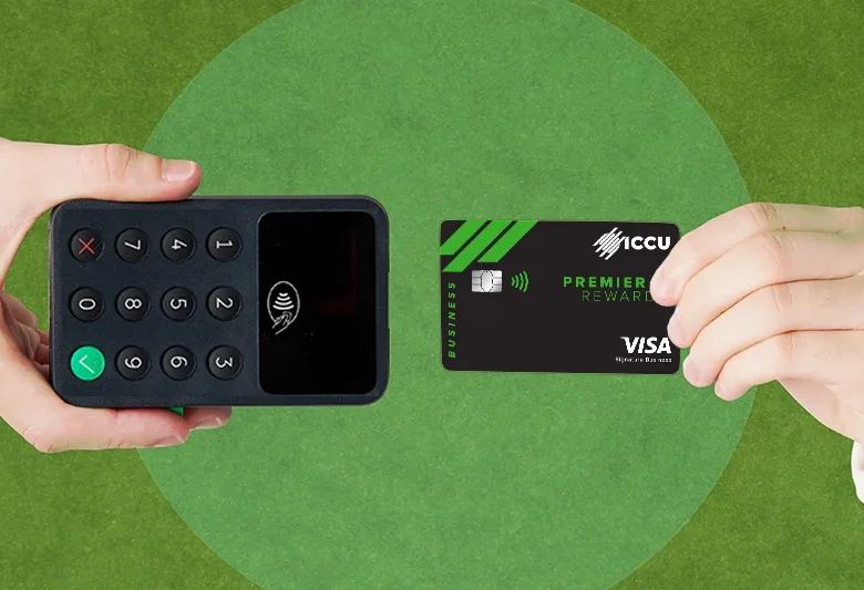 Hand holding ICCU®168一分钟极速赛车体彩官网 Premier Rewards Visa Credit Card near a card reader for contactless payment.
