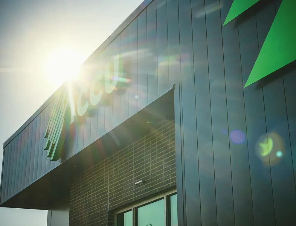 Modern ICCU branch exterior with sunlight reflecting off a sleek metal façade