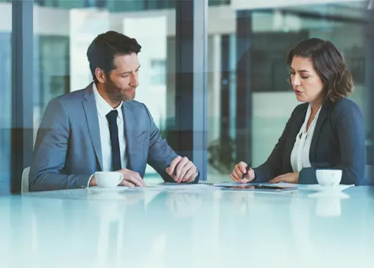 man and woman in business attire going over financial information